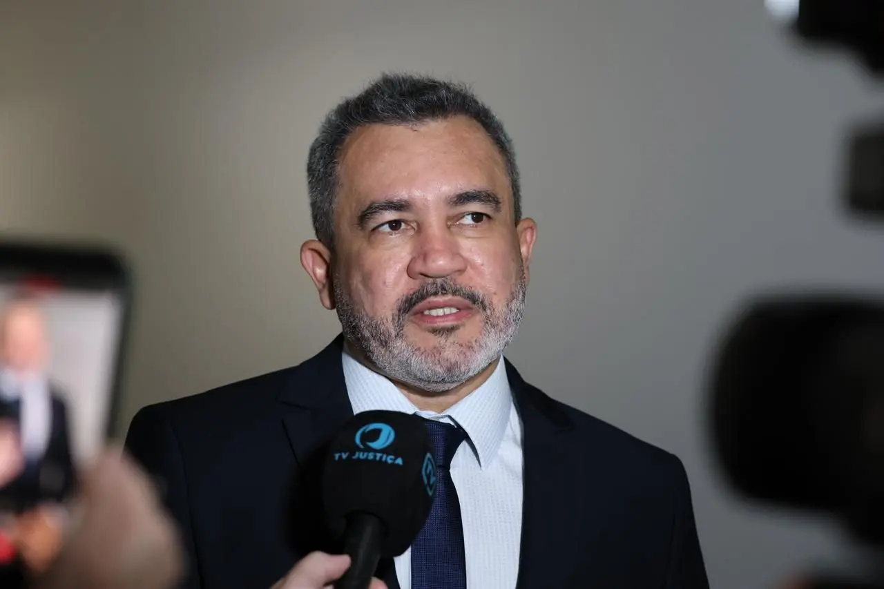 O juiz Antônio Veloso Peleja Júnior, um homem pardo de cabelos grisalhos e barba aparada vestindo terno e gravata escuros, concede uma entrevista para a TV Justiça.