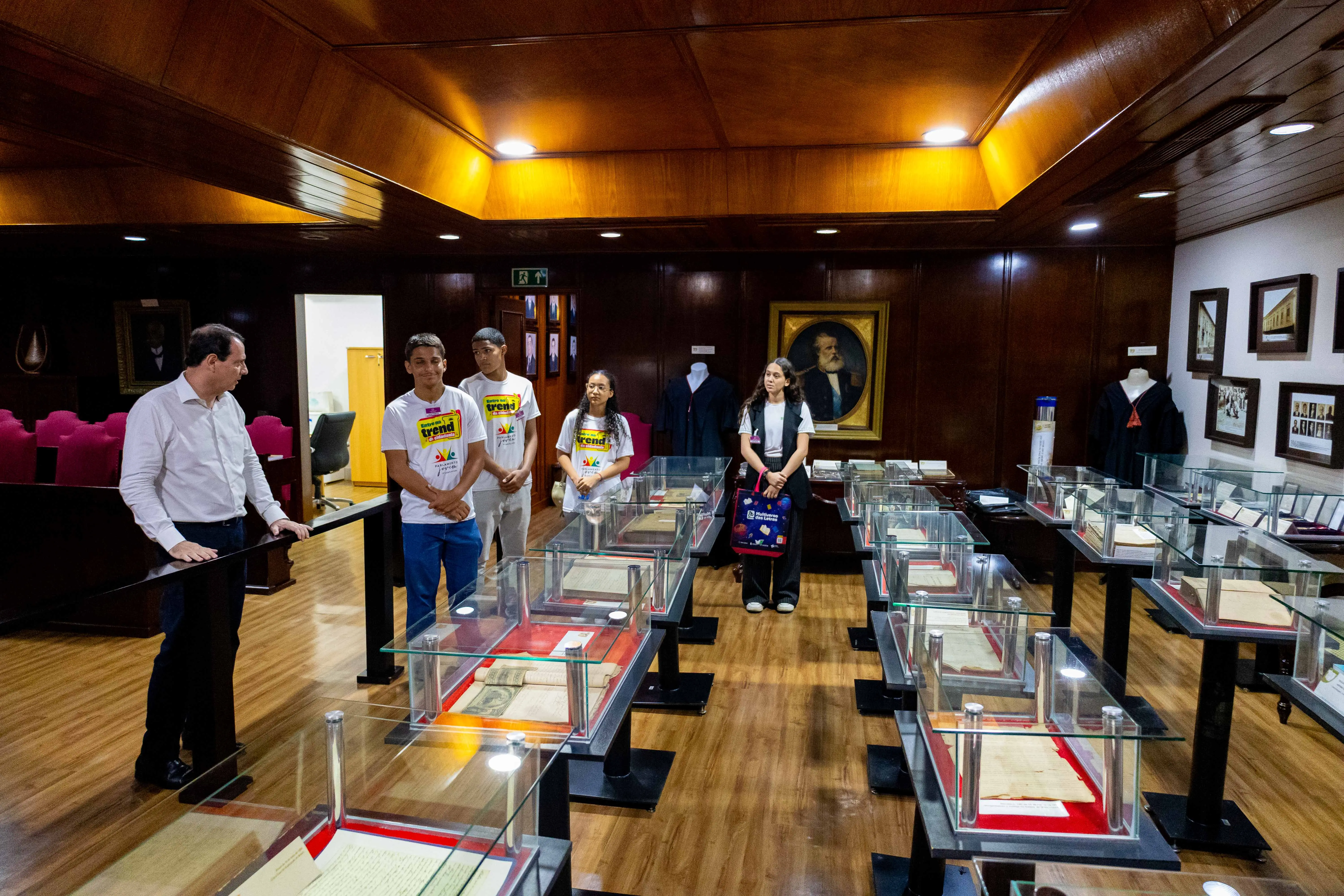 Imagem mostra estudantes observando documentos em aquários de proteção no memorial do Judiciário.